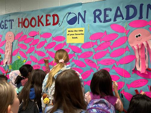 Elementary students crowded around an Interactive book display